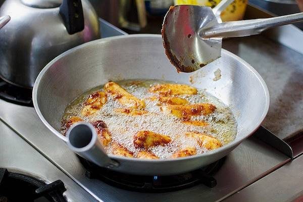 Bananas frying in a pan of oil.