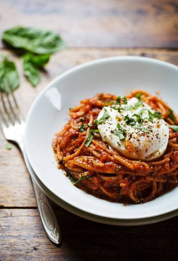 Spaghetti Marinara with Poached Eggs on a white plate with a fork.
