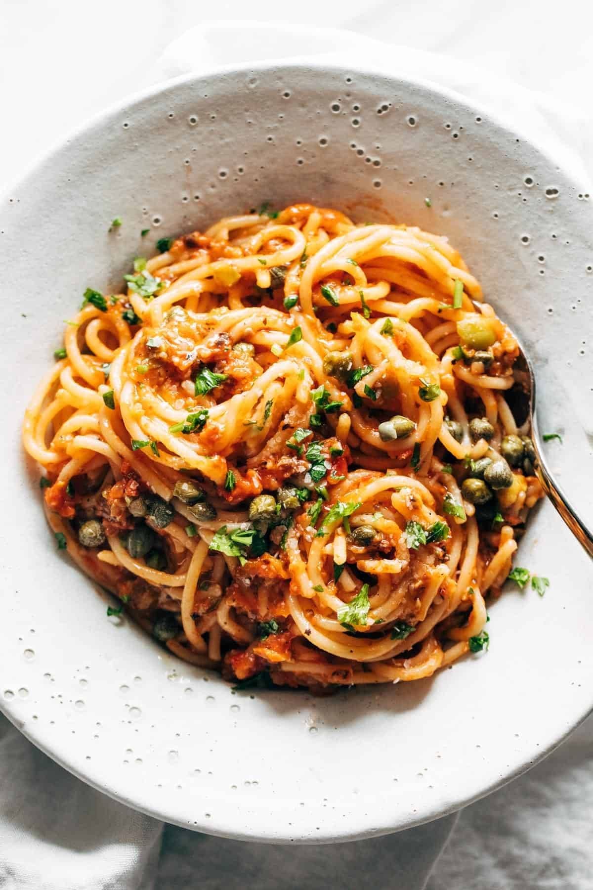 Spaghetti with capers and basil ina. bowl.