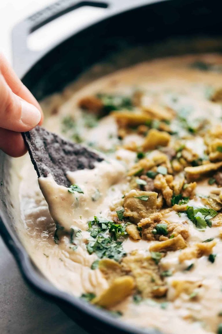 Dipping a chip into spinach queso.