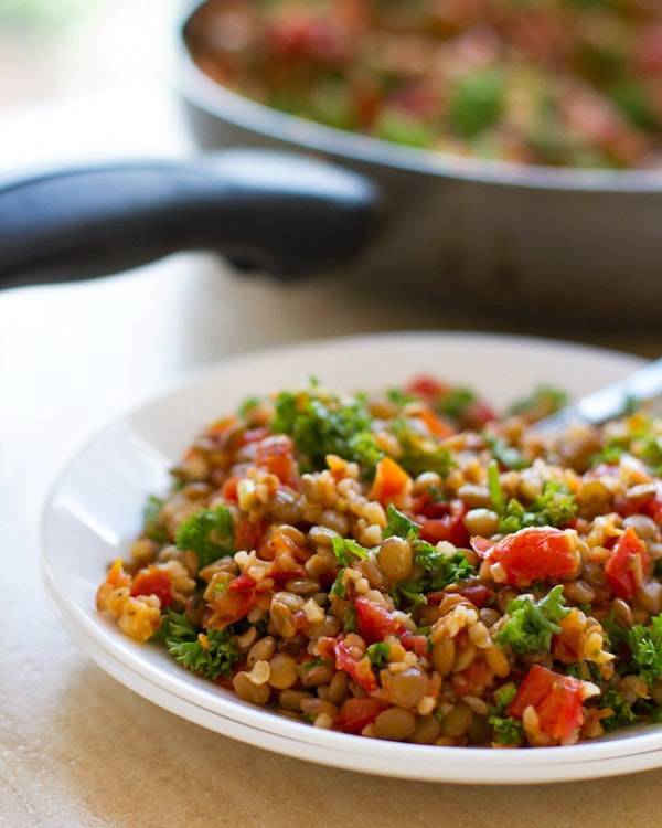 Garlic and tomato lentil salad on a white plate.