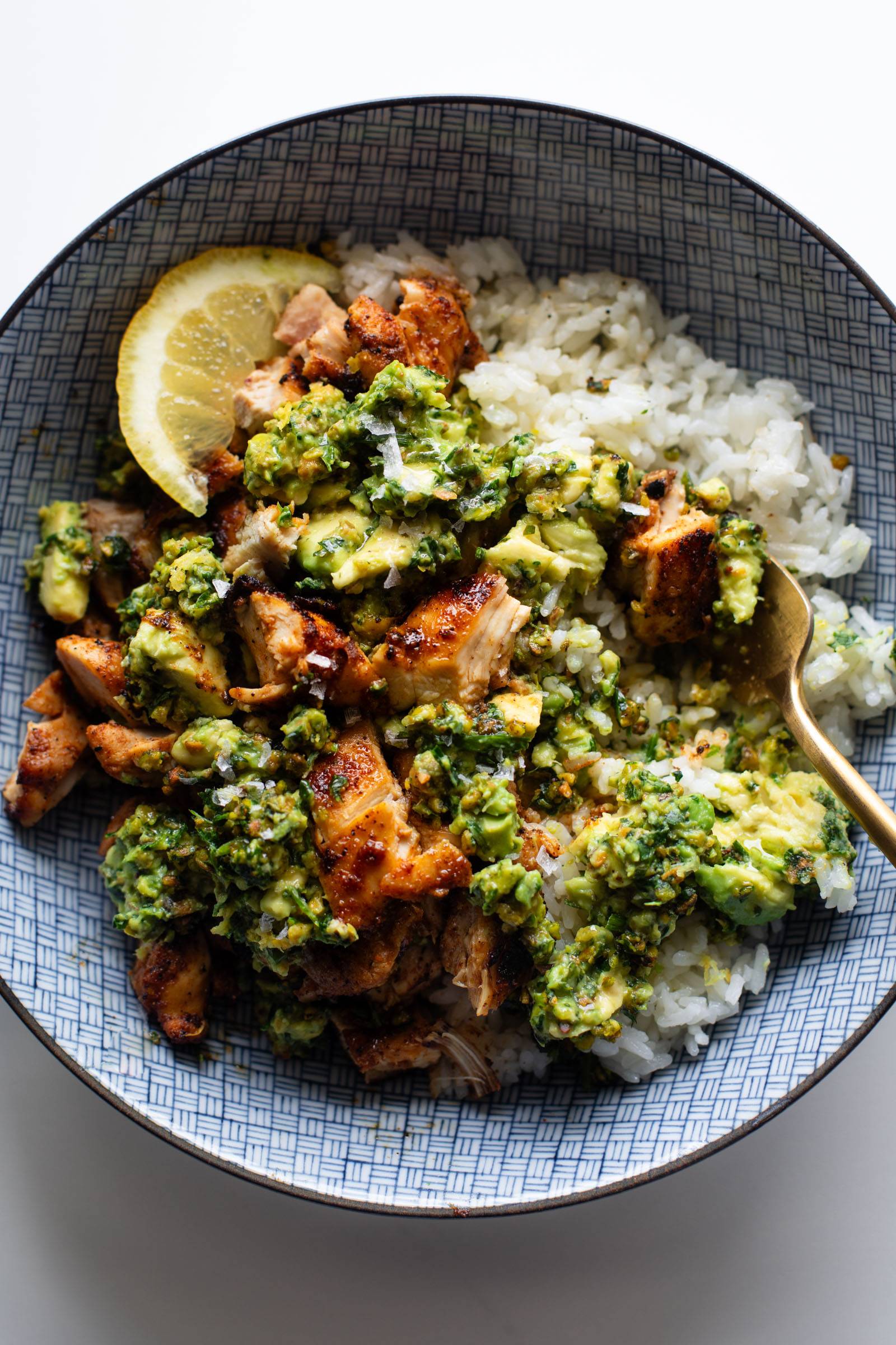 Chipotle chicken in a bowl with rice and chunky pistachio sauce.
