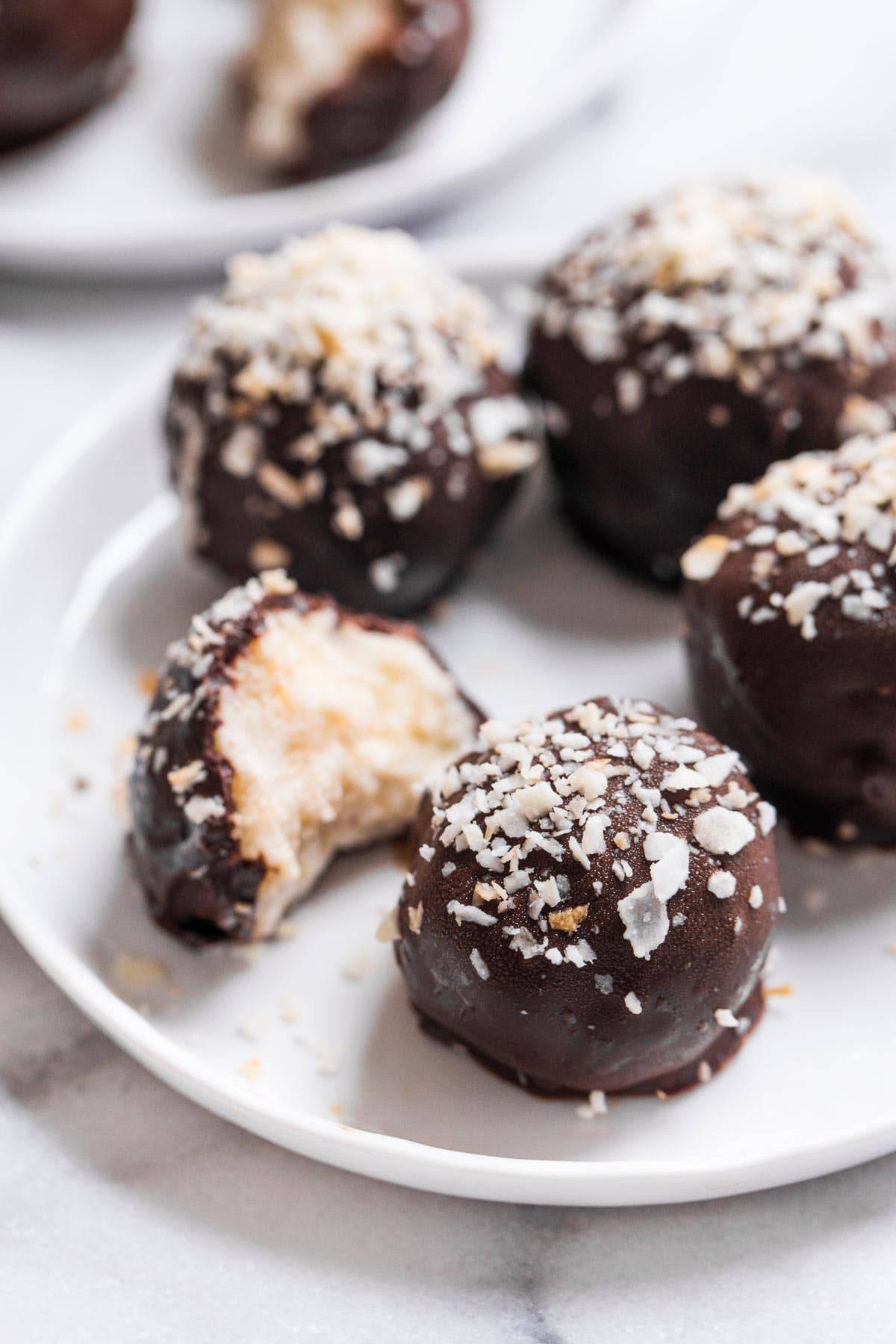Dark chocolate coconut bites on a white plate.