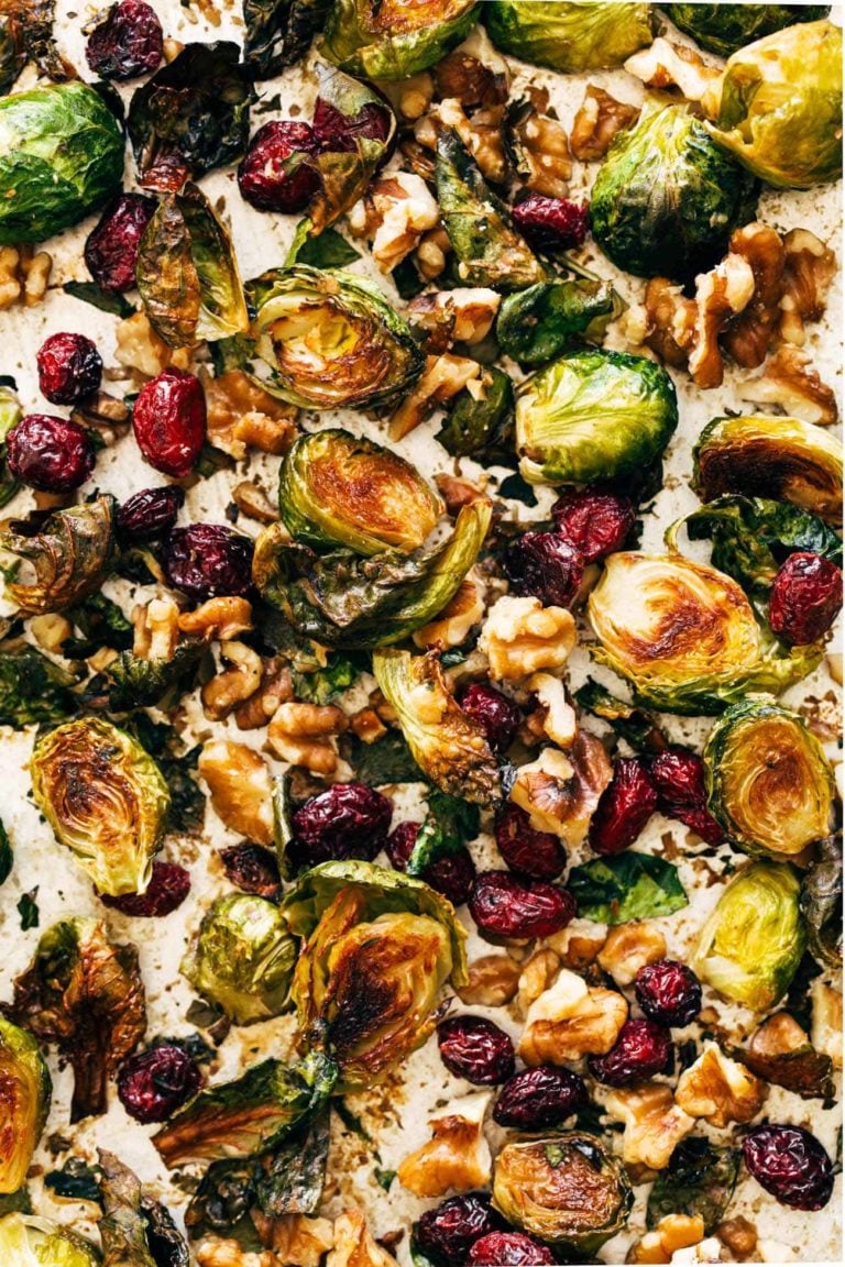 Roasted brussels sprouts on a sheet pan with cranberries and walnuts.