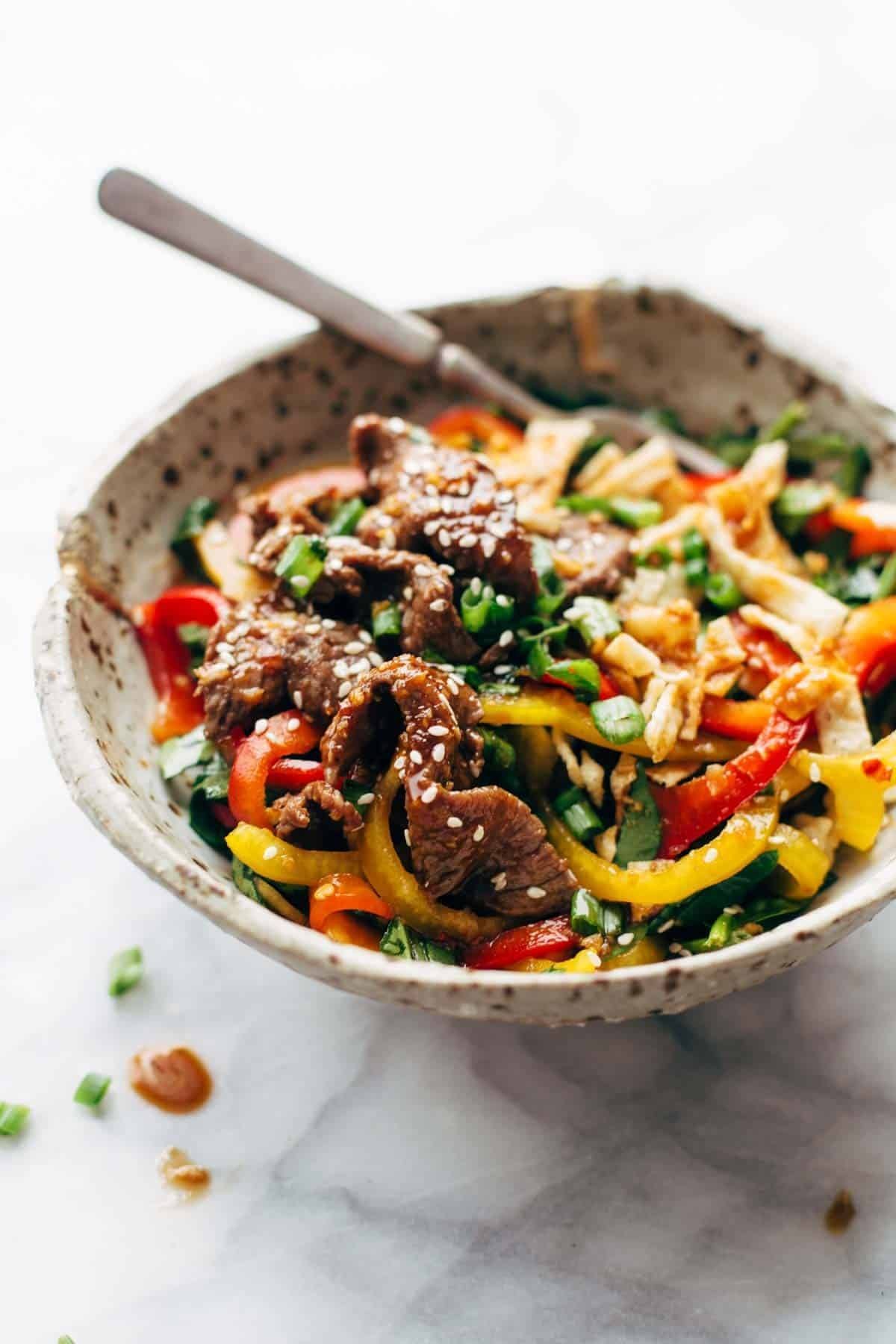 Korean BBQ Steak Bowls! Featuring Korean BBQ steak, bell peppers, scallions, greens, wonton strips, a spicy sesame ginger dressing. | pinchofyum.com