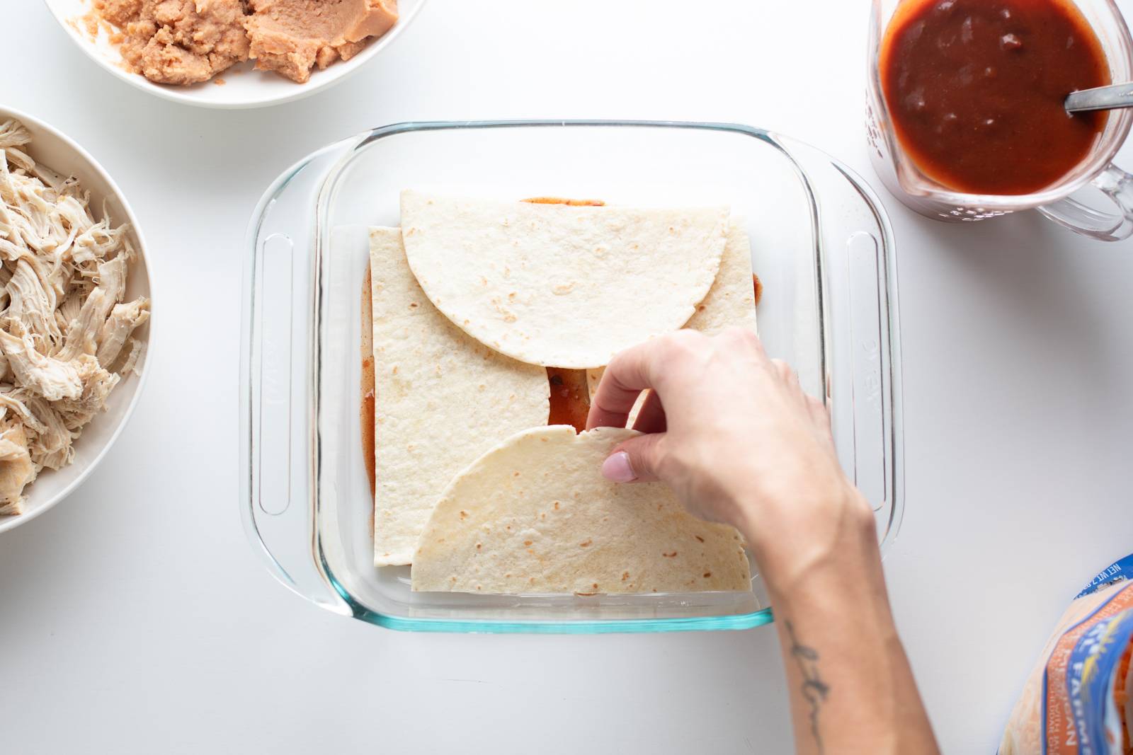 Layering tortillas in a glass baking dish.
