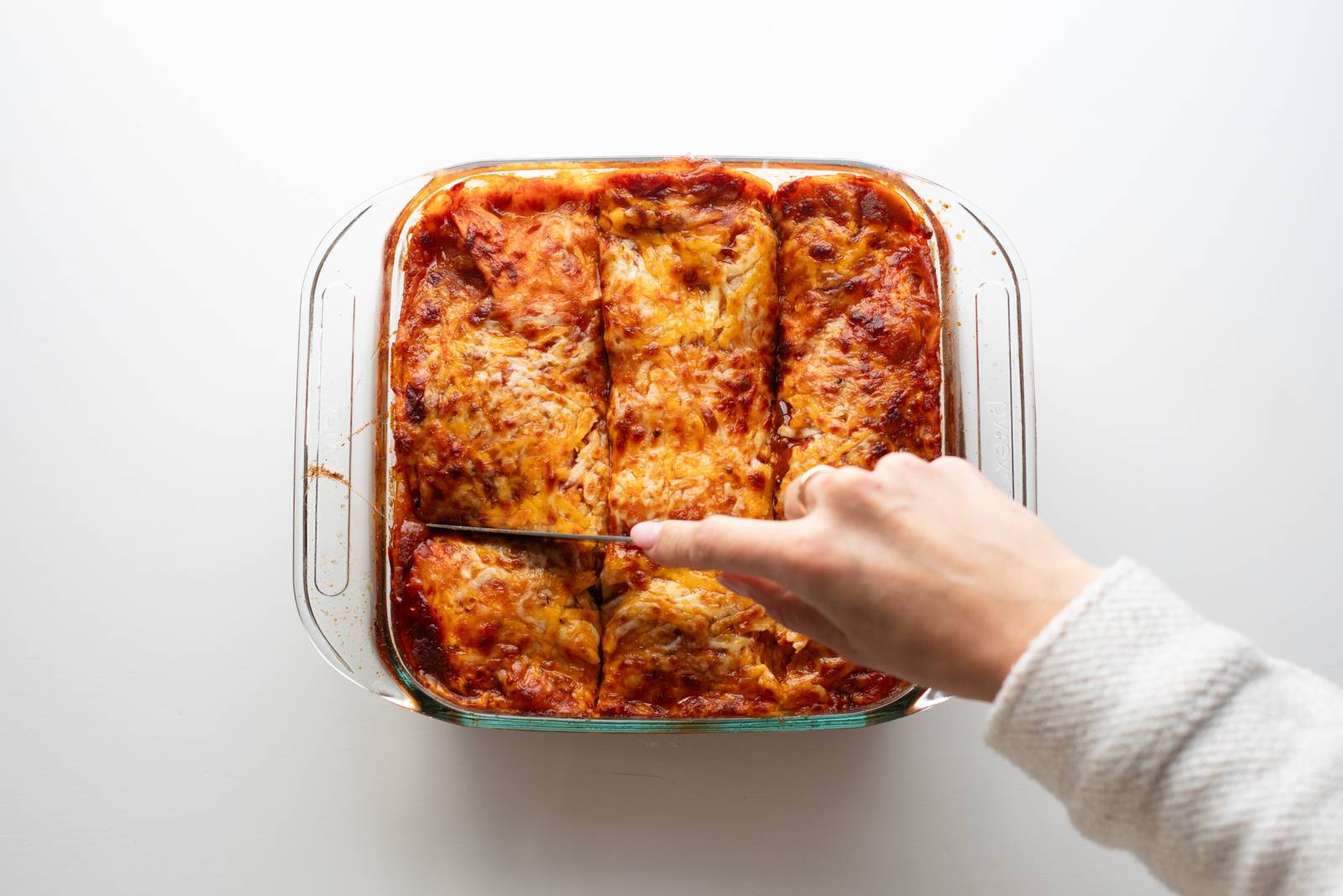Sliced chicken enchilada casserole in a baking dish.
