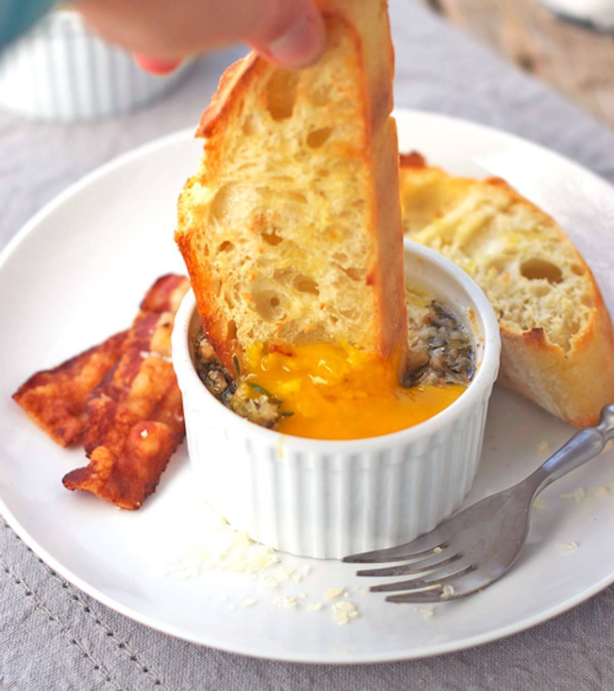 Piece of bread dipping into parmesan baked eggs.